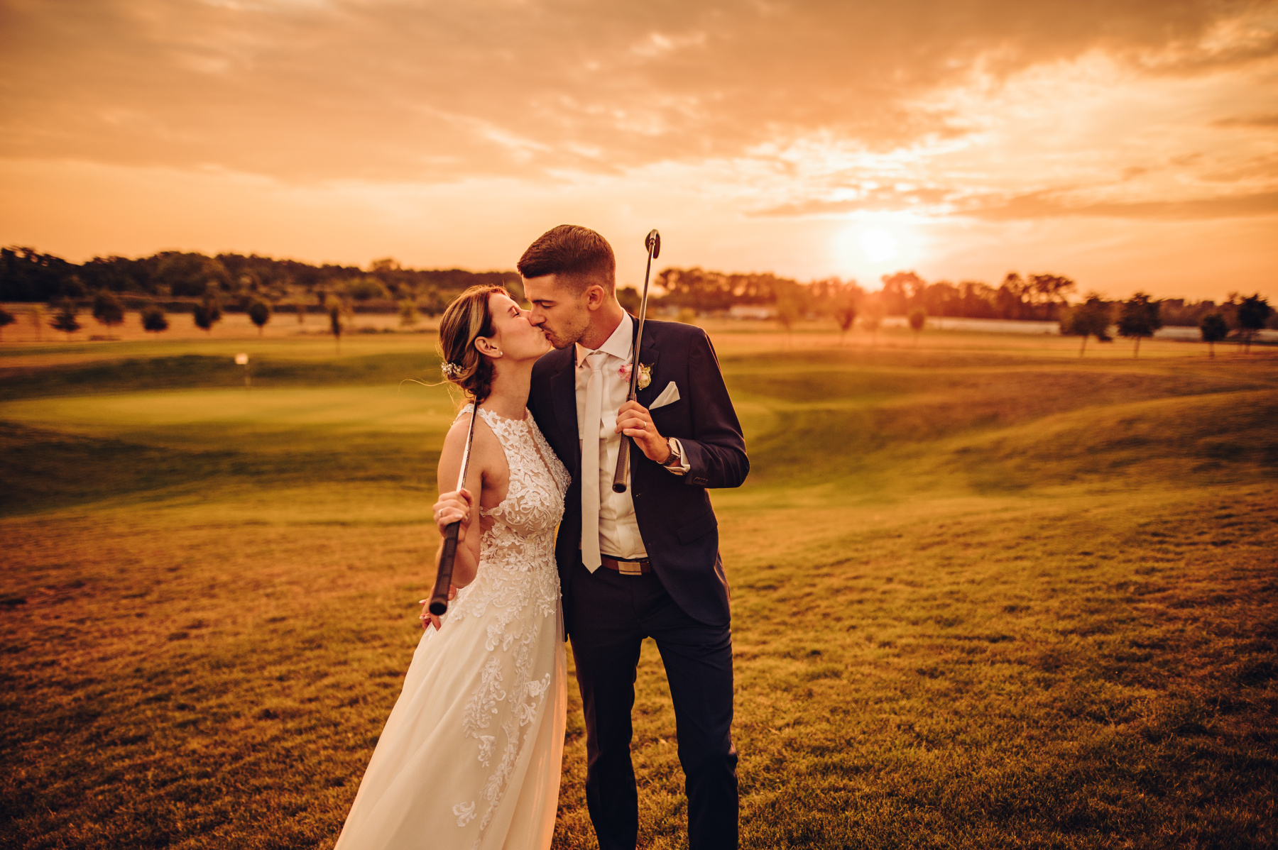 Svatební pár na procházce po golfovém hřišti při západu slunce